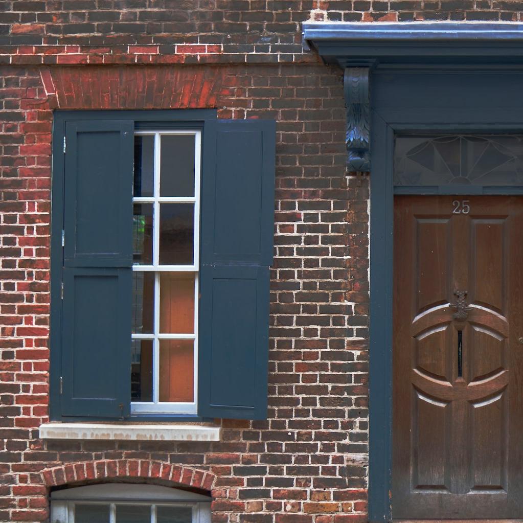 a brick building with blue shutters and a wooden door